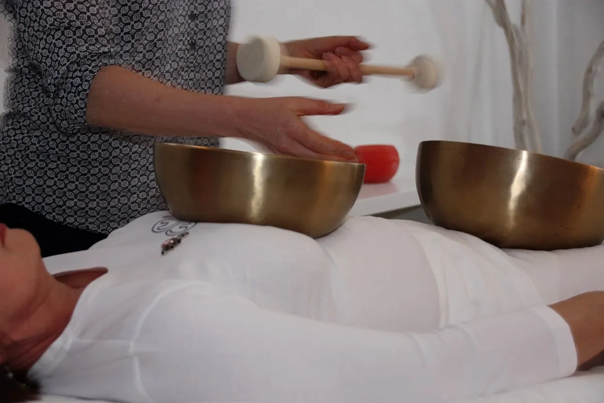 Klangschalen liegen auf dem Bauch einer liegenden Person